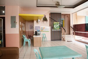 Un vestíbulo de hotel con un mostrador de recepción, una escalera y un cartel verde de GV Hotels.