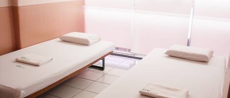 Two single beds in a hotel room with a view of a balcony.