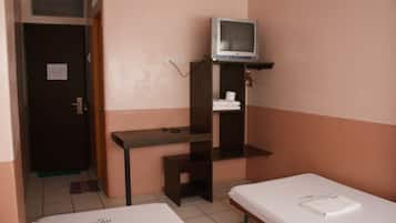 Una camera d'albergo piccola con un letto singolo, una TV su un ripiano e una porta che dà su un'altra stanza.