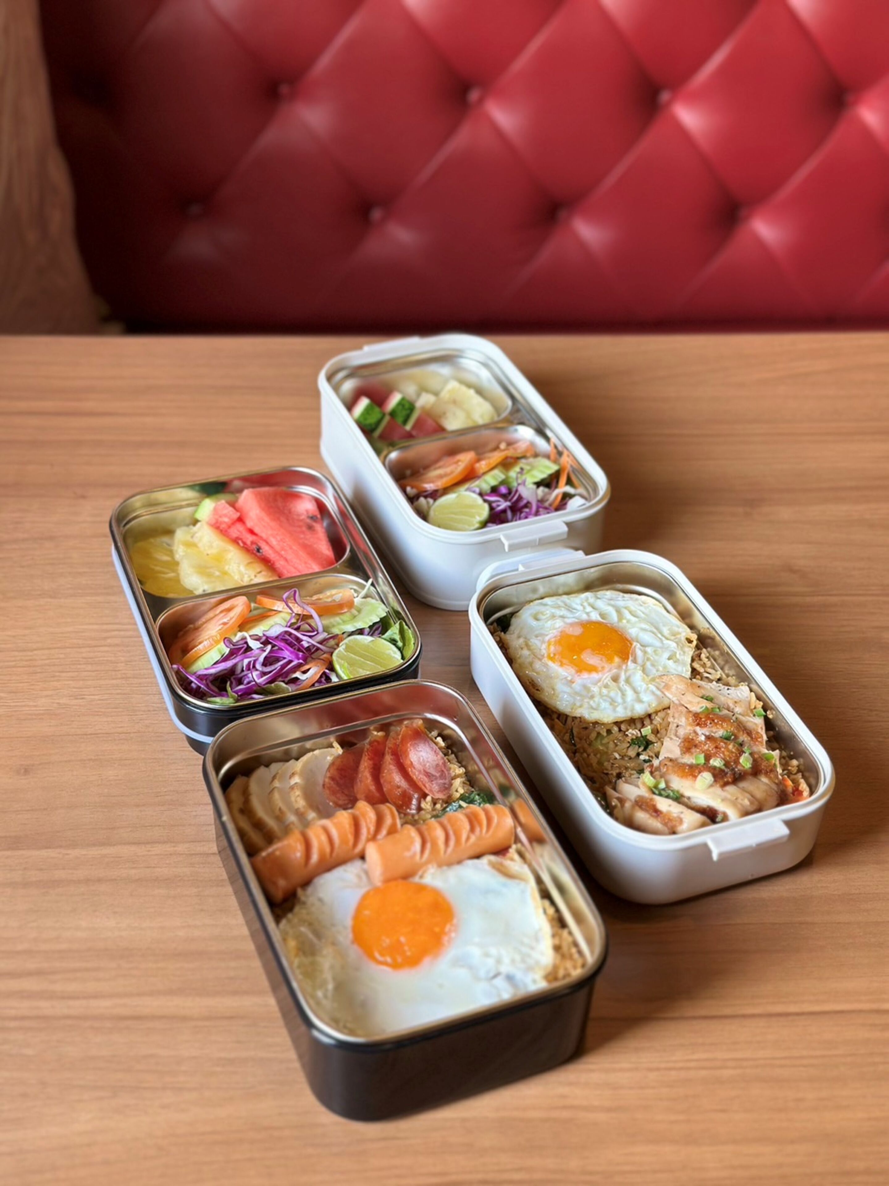 Cuatro recipientes para comida sobre una mesa de madera.