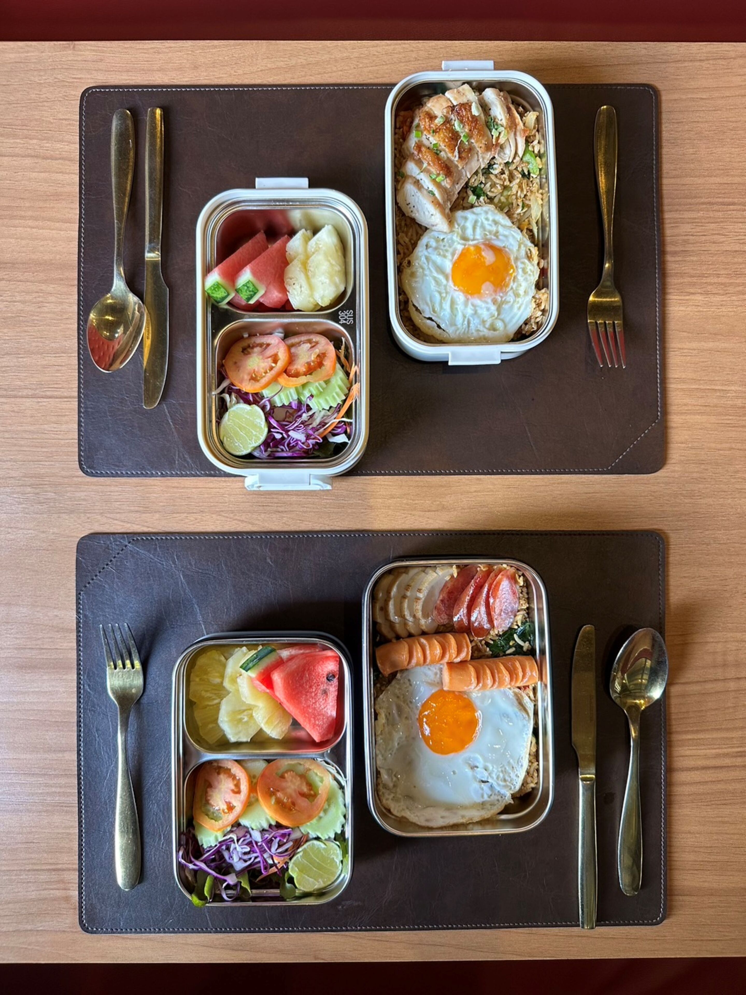 Two meal trays on a table with cutlery.