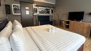 Ein Hotelzimmer mit einem Bett, einem Schreibtisch, einem Fernseher und einem kleinen Schrank.