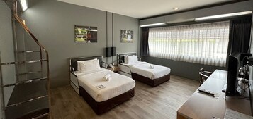 Habitación de hotel con dos camas, un escritorio, una silla, un televisor y una escalera.