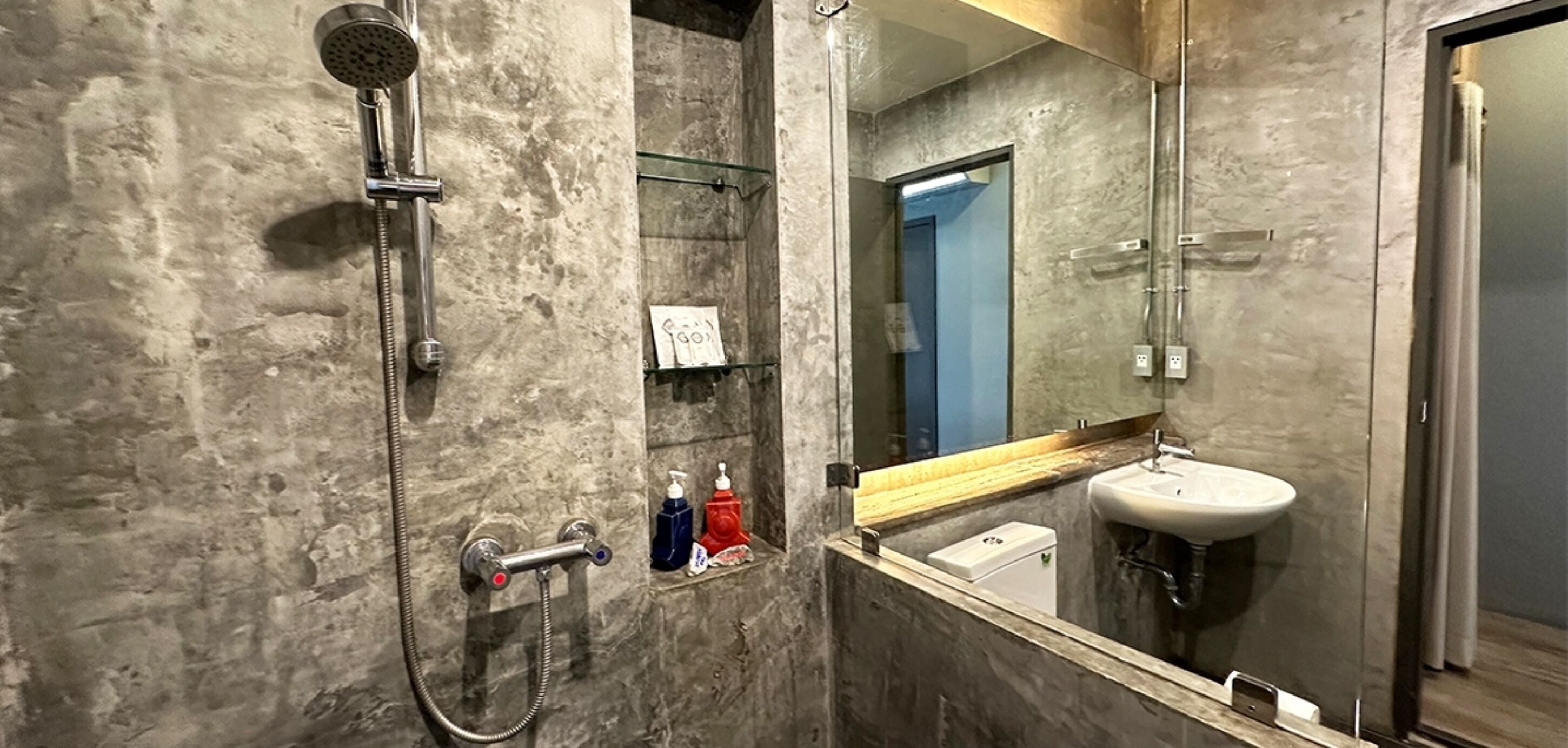 A modern bathroom with a glass shower enclosure, a built-in sink, and a large mirror.