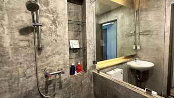A modern bathroom with a glass shower enclosure, a built-in sink, and a large mirror.