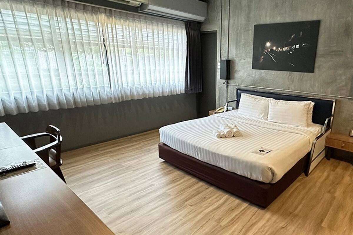 A modern hotel room with a large bed, a desk, and a wardrobe.