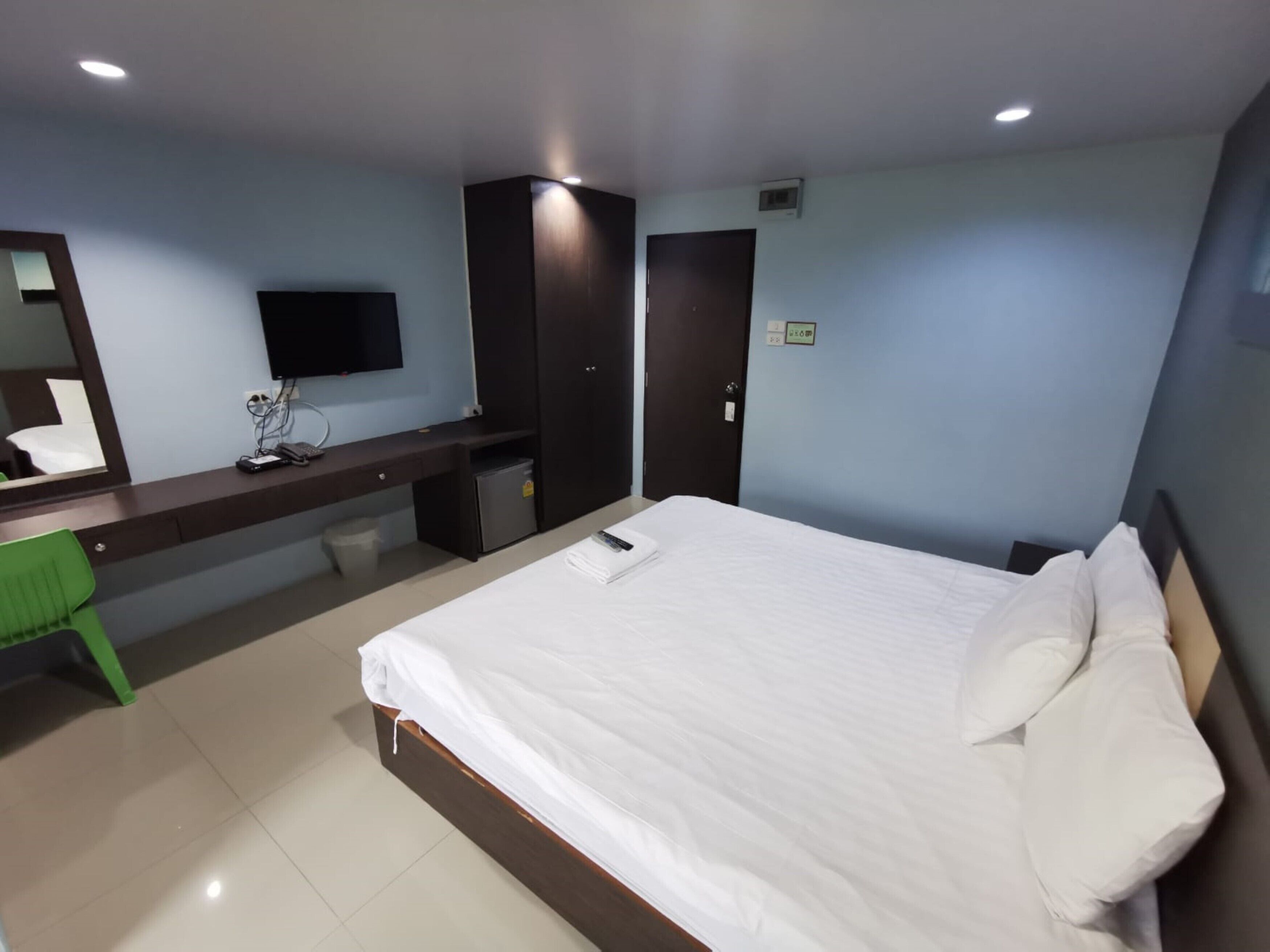 Habitació d'hotel amb llit, escriptori amb ordinador, cadira, televisió i armari.