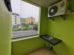 A small, green-walled room with a window, a sink, and a wall-mounted air conditioner. - The Peak Songkhla (Songkhla)