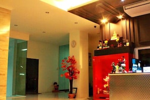 A room with a wooden ceiling, a red decorative shelf, and a potted plant. - Able Resident Hat Yai (Hat Yai)