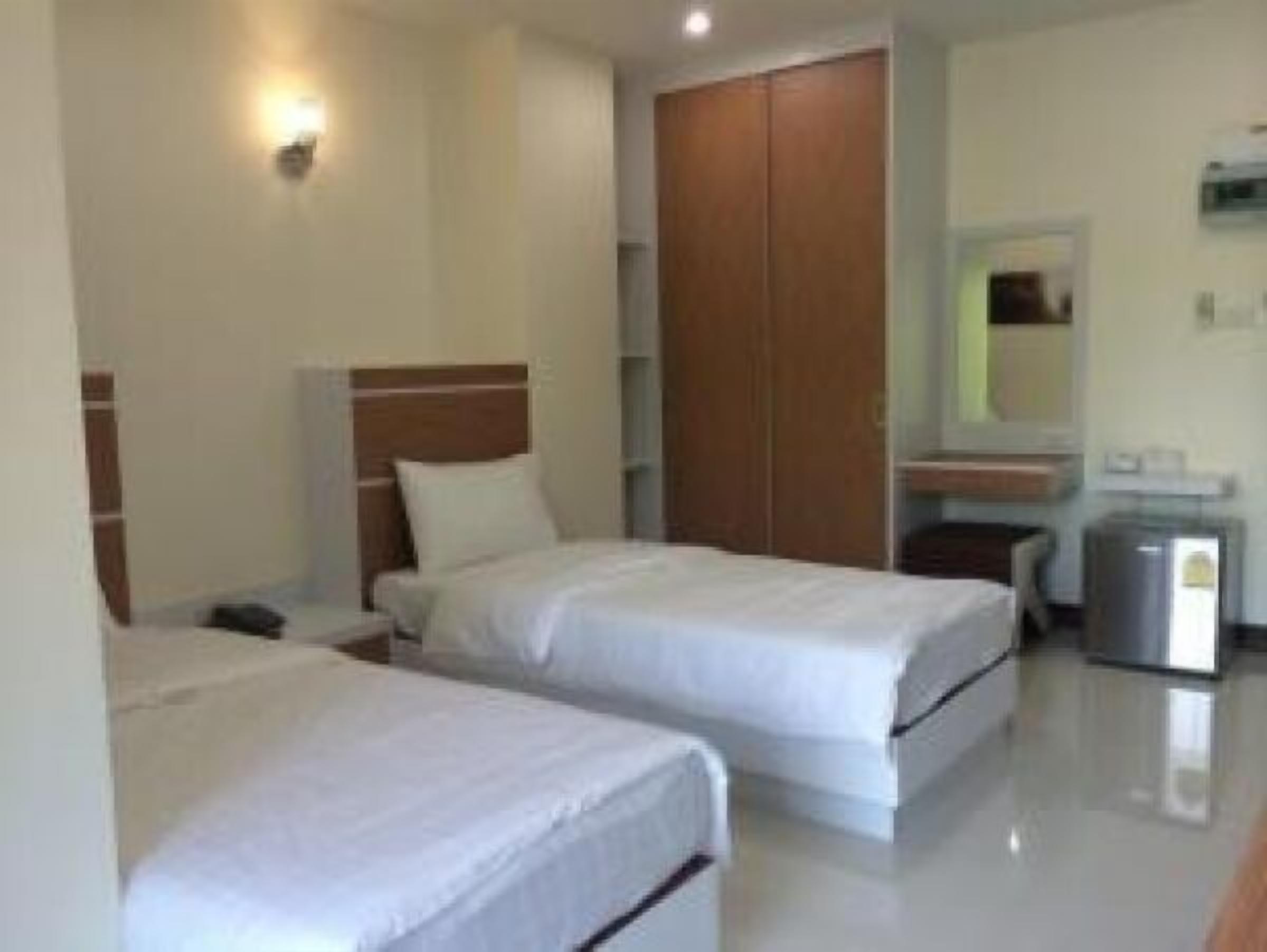 A hotel room with two single beds, a wooden wardrobe, a small desk, and a mirror.