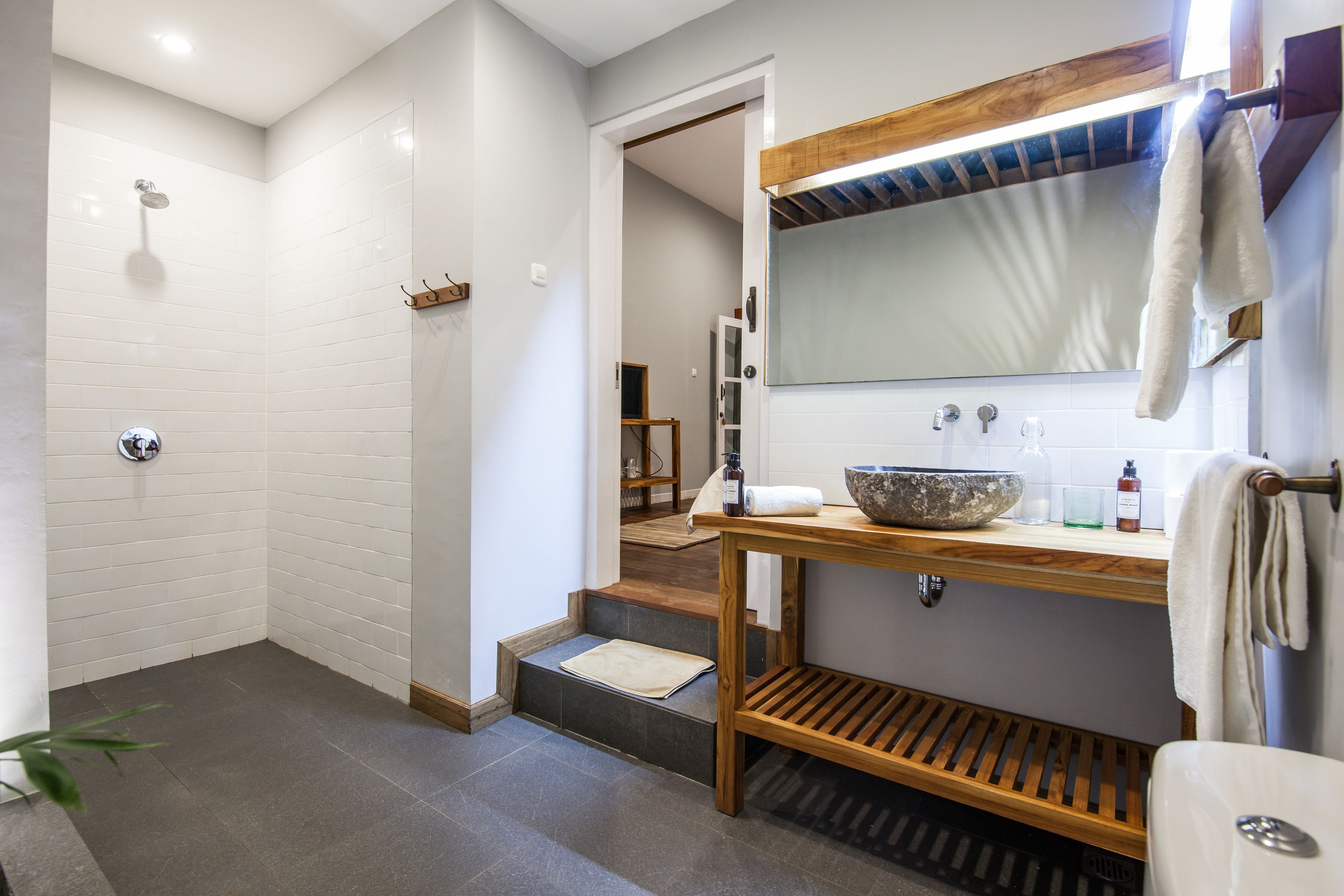 A modern bathroom with a shower, a wooden vanity, and a large mirror.