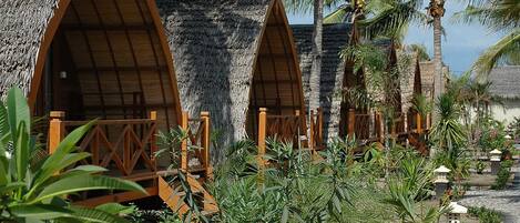 A resort with thatched-roof cottages, palm trees, and a paved walkway.