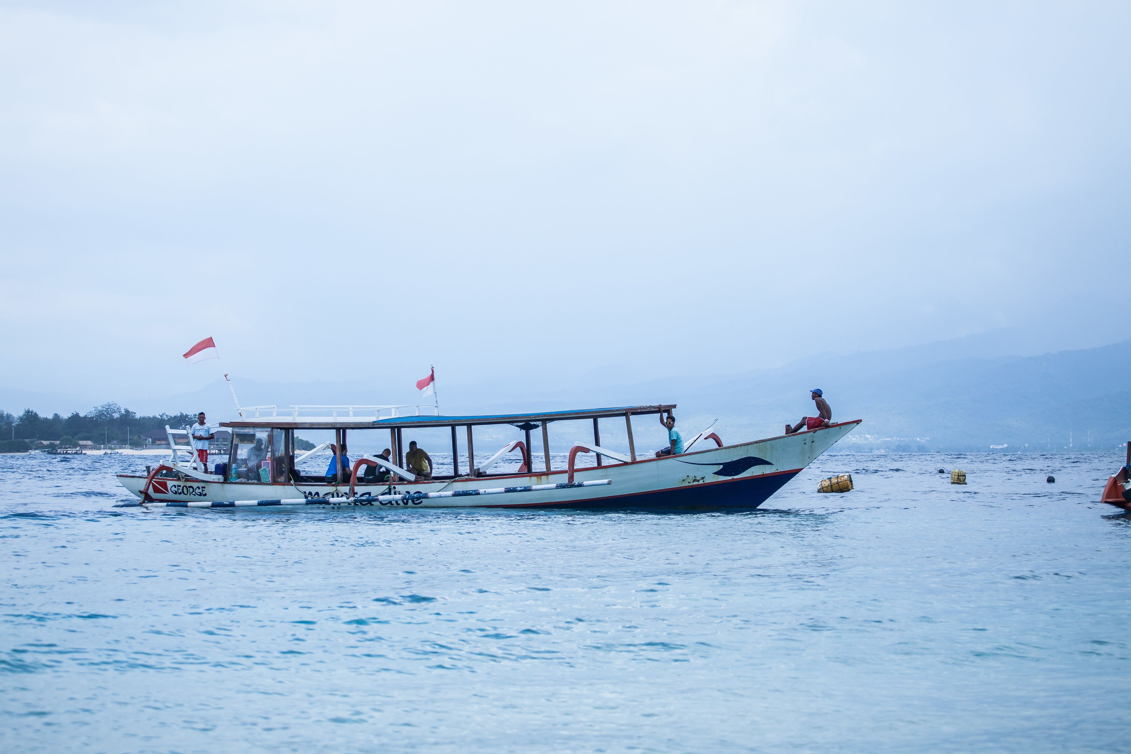 A boat with passengers, a flag, and buoys in the water.