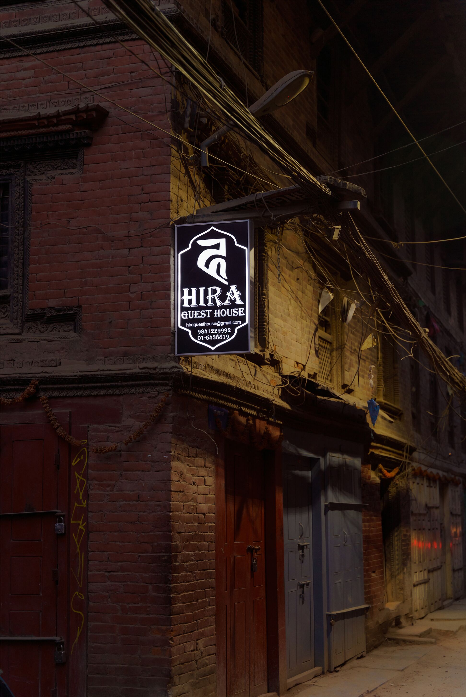 A sign for "HIRA GUEST HOUSE" with contact information.