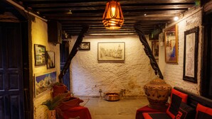 A cozy room with a fireplace, a sofa, and a table with a vase of flowers. - Hira Guest House (Lalitpur)