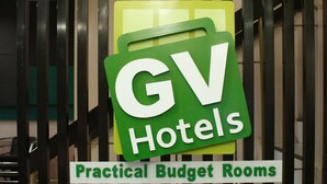Ein Schild für GV Hotels mit dem Text 'Praktische Budgetzimmer' an einem Metallgitter.