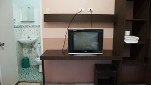 Ein Badezimmer mit Waschbecken, Toilette und einem an einer Holzablage befestigten Fernseher.
