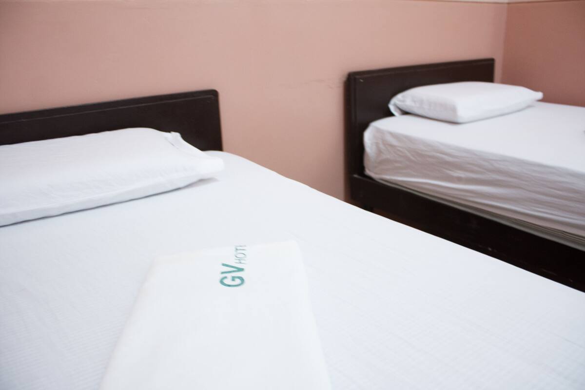 Ein Hotelzimmer mit zwei Einzelbetten, jeweils ausgestattet mit einer weißen Matratze und einem Kopfkissen.