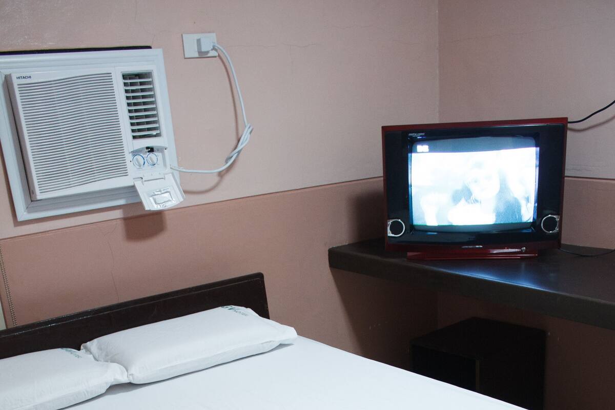 Ein Hotelzimmer mit Bett, Fernseher und Klimaanlage.