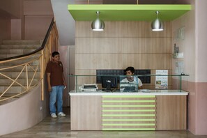 A reception desk with a wooden finish, two pendant lights, and a glass partition. - GV Hotel Borongan (Borongan City)