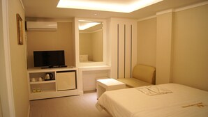 A hotel room with a bed, a television, a small table, a chair, and a mirror. - Princess Hotel (Seoul)