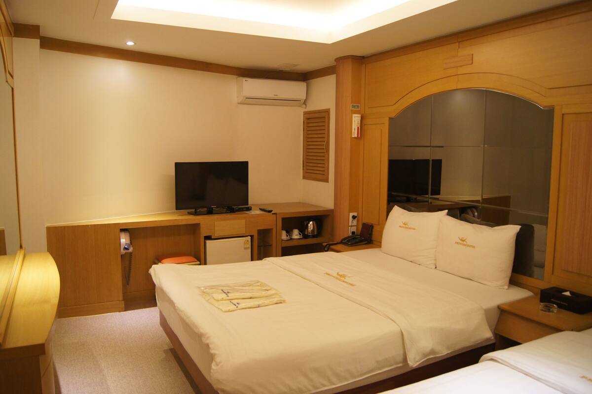 A hotel room with a bed, a desk with a computer, a television, and a mirror.