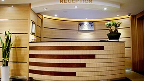 A reception area with a wooden reception desk, a potted plant, and a world map on the wall. - Princess Hotel (Seoul)