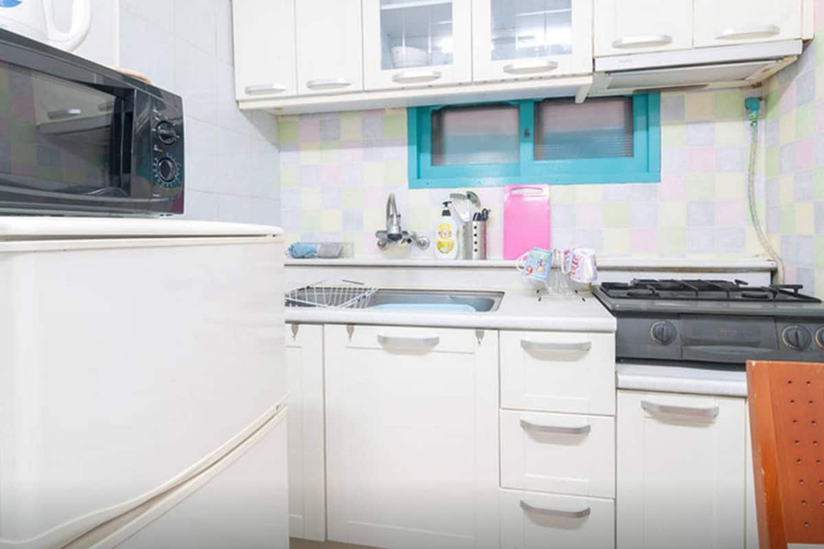 A compact kitchen with white cabinets, a microwave, a sink, and a stove.