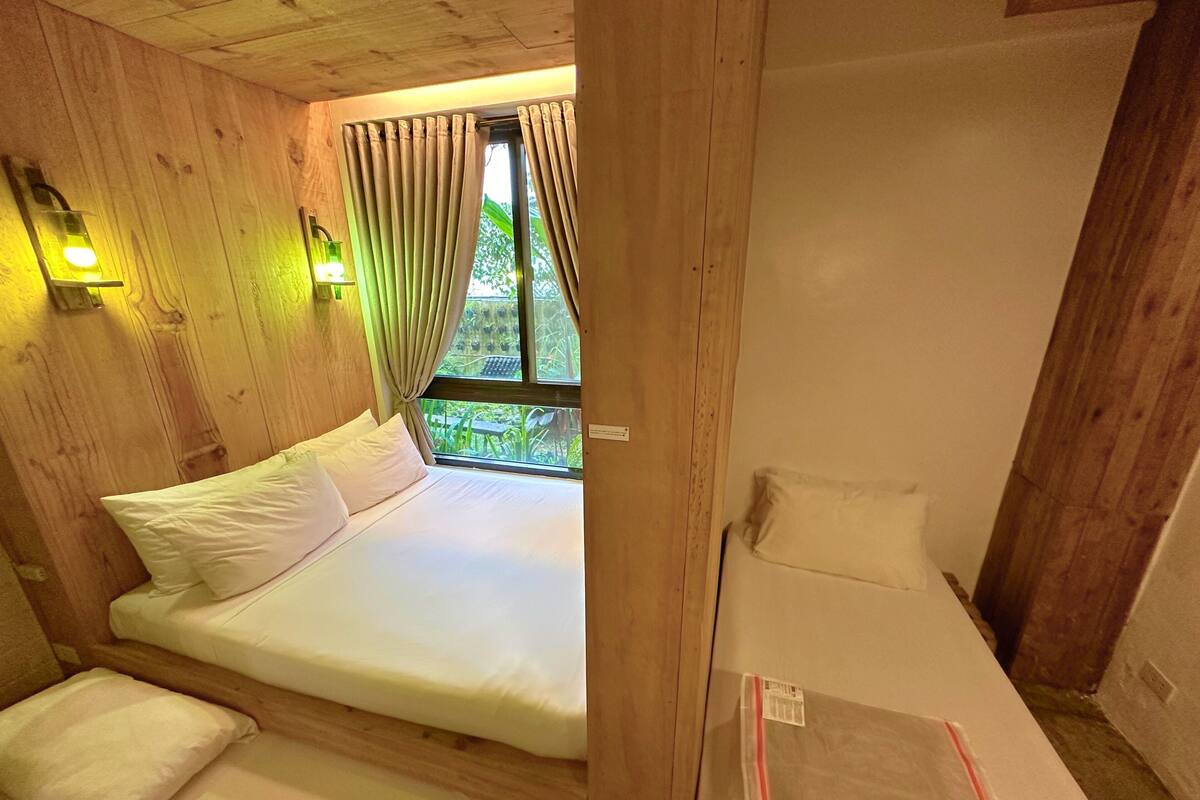Une pièce en bois avec un lit, un plus petit lit et une fenêtre avec des rideaux.