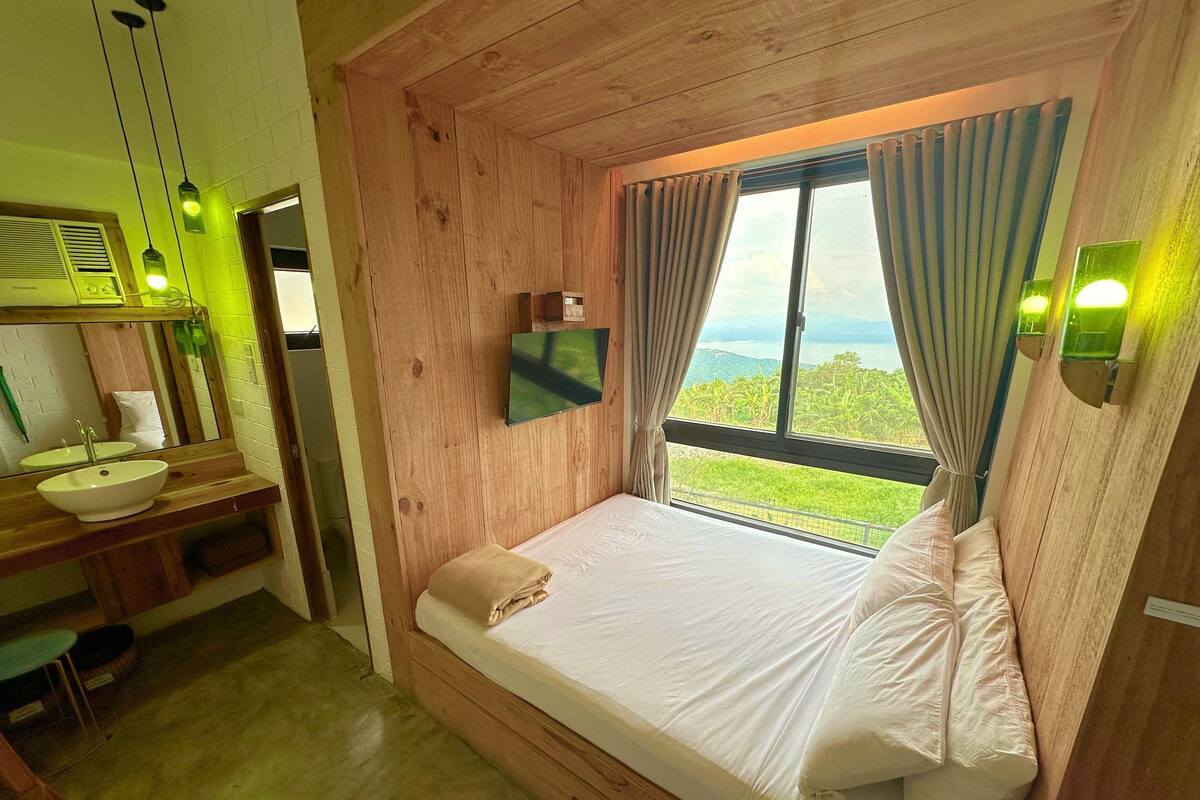Une pièce en bois avec un lit, un lavabo et une fenêtre donnant sur un beau paysage.