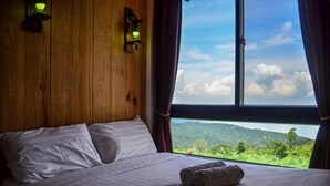 Une chambre d’hôtel avec un grand lit, une vue sur un paysage montagneux et un mur en bois.