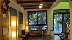 Un coin lecture accueillant, avec des étagères à livres, des fauteuils confortables et une grande fenêtre donnant sur l’extérieur.