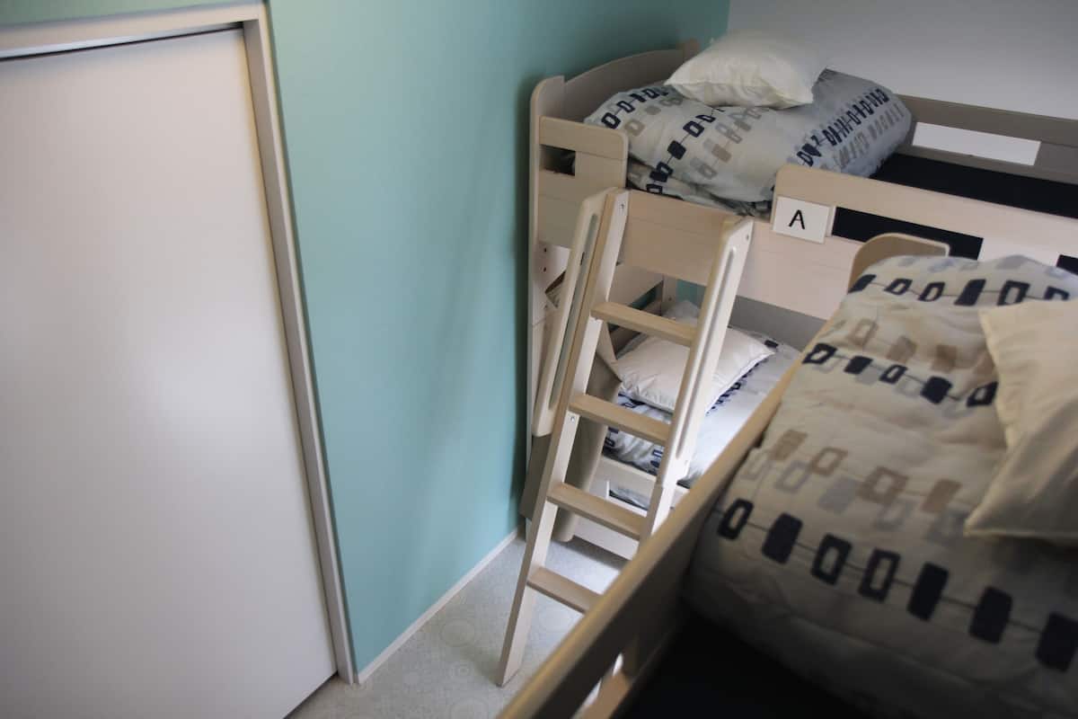 A bunk bed with a ladder, a white door, and a blue wall.