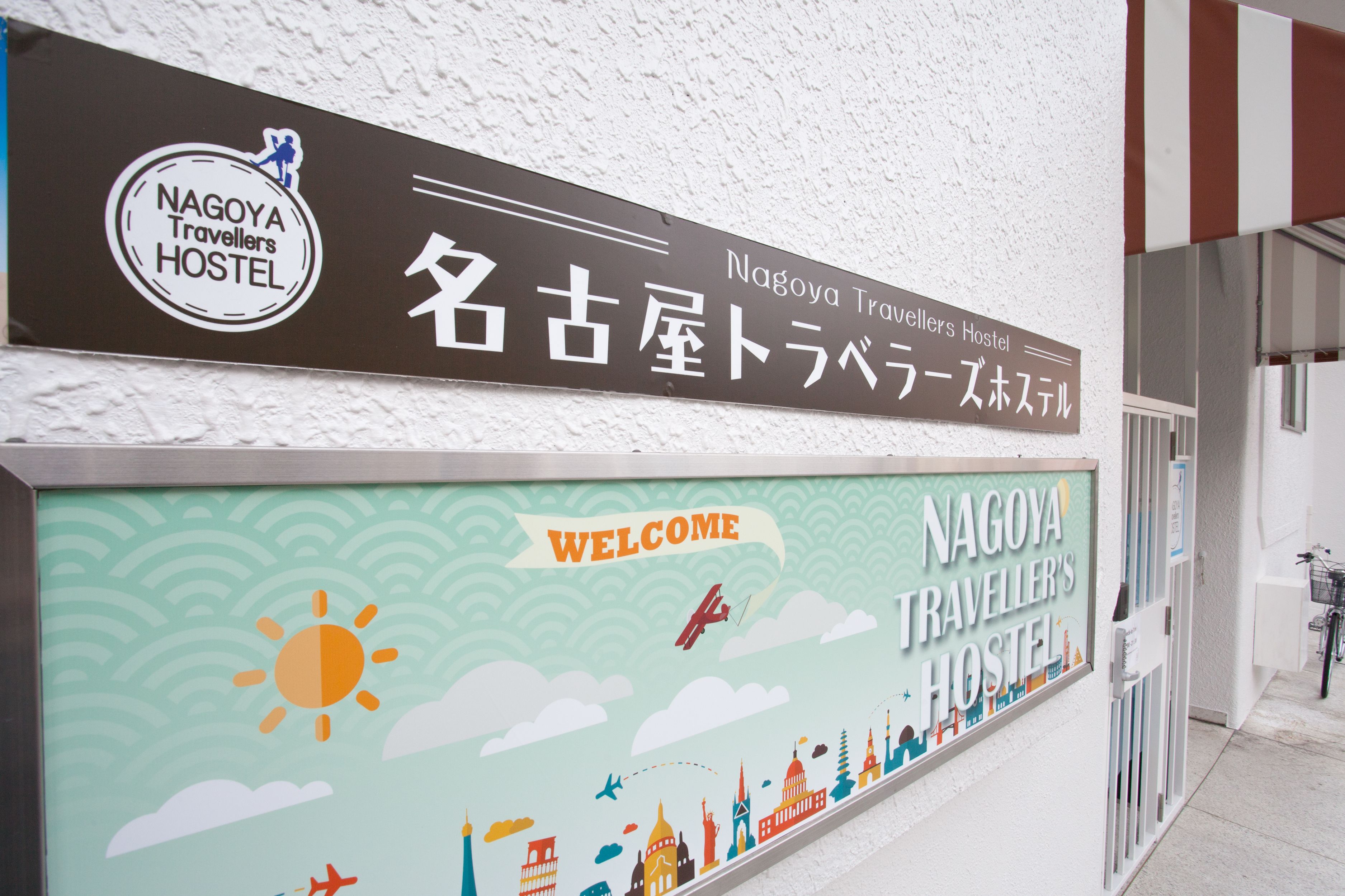 A hostel sign with a welcome message and travel-themed decorations.