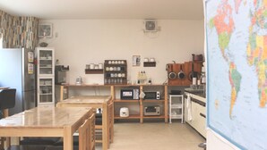 Cuina compacta amb zona de menjador, equipada amb nevera, microones i diversos electrodomèstics.