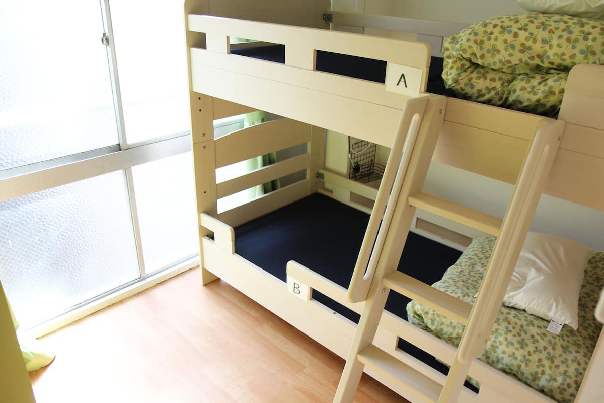 A bunk bed with two levels, each with a mattress and pillows. There is a ladder for access to the upper bunk.