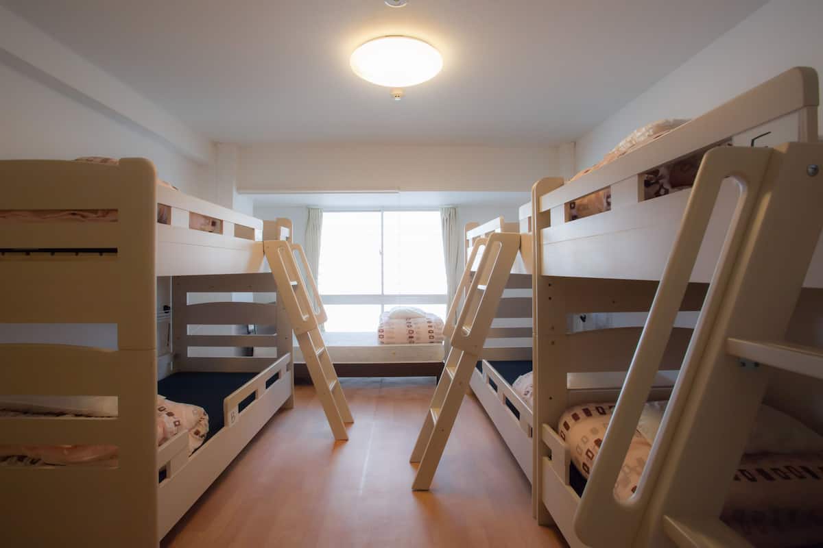 A room with bunk beds, a window, and a ceiling light.