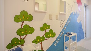 Habitació infantil amb un mural a la paret, un mirall i una petita estant blanca.