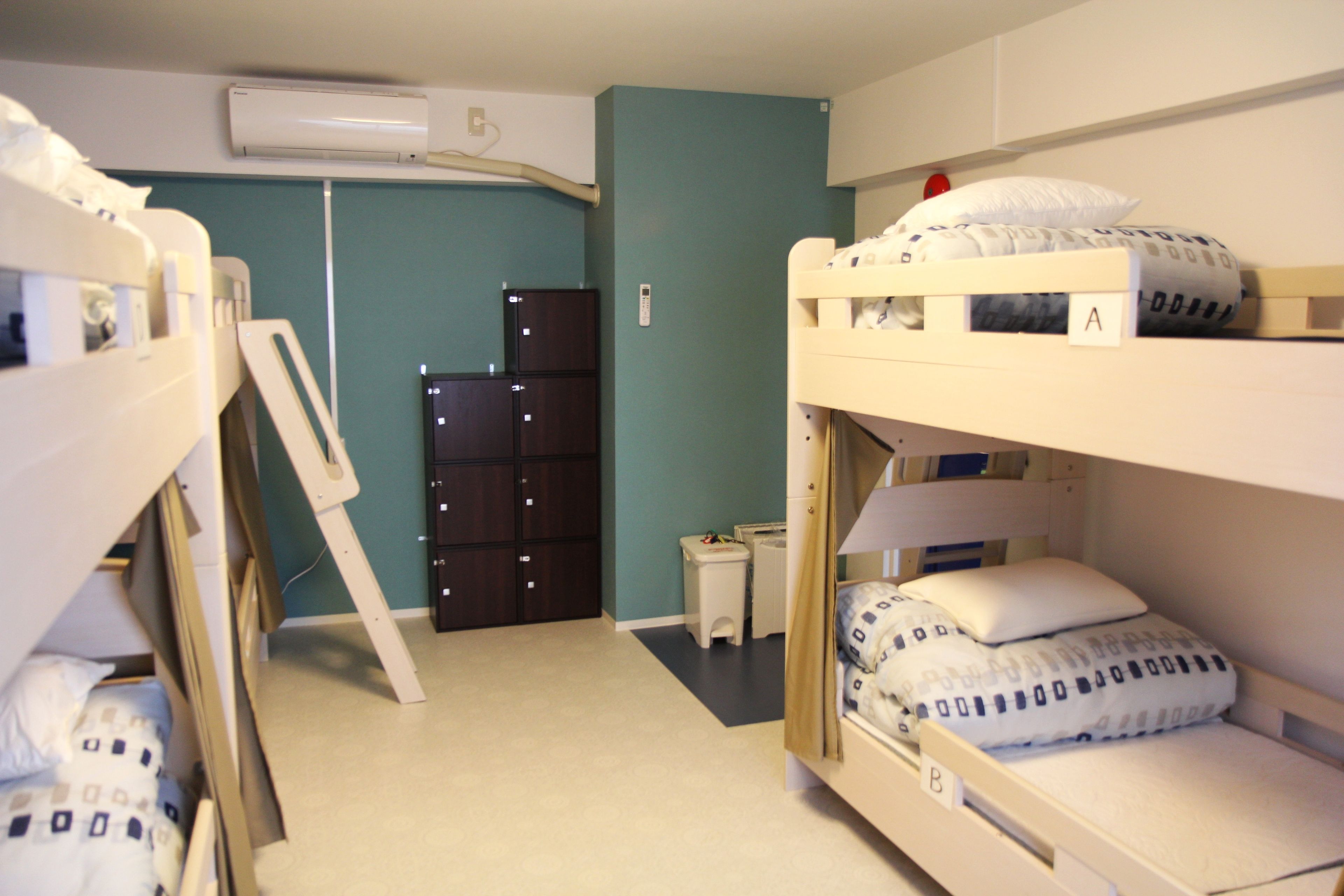 A bunk bed room with a desk and a wardrobe.