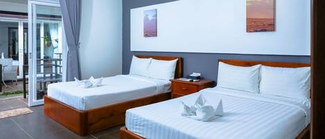 Habitación de hotel con dos camas, puerta corrediza al exterior y obras de arte en las paredes.