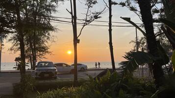 Vista del atardecer con una carretera, coches estacionados y peatones.