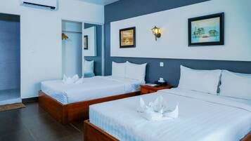 Een hotelkamer met twee bedden, een houten hoofdeinde, een nachtkastje en kunstwerken aan de muur.