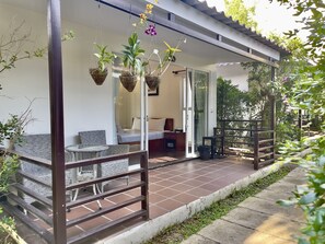 A covered outdoor seating area with wicker furniture and hanging plants. - Sea Breeze Resort (Sihanoukville)