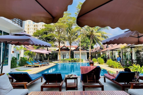 Una piscina al aire libre, sombrillas, sillones reclinables de piscina