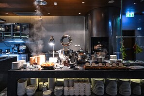 A buffet setup with various dishes, utensils, and stacked plates. - Amara Bangkok (Bangkok)
