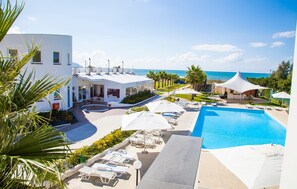 Un resort con piscina, tumbonas y vistas al mar.