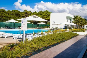 A swimming pool with lounge chairs and umbrellas, surrounded by greenery and a modern building. - Medea Beach Resort (Capaccio-Paestum)