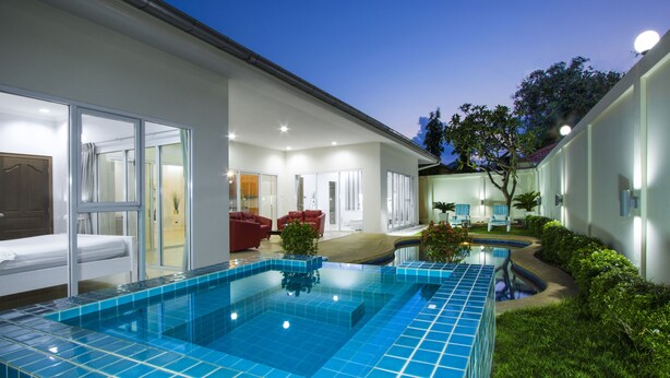 Un hôtel moderne doté d’une piscine, d’espaces de détente intérieurs et extérieurs, et d’une façade bien éclairée.