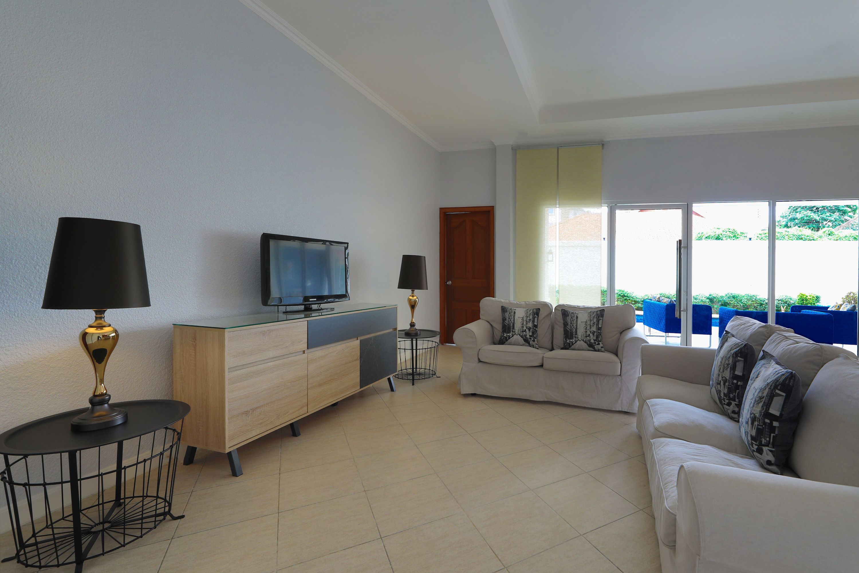 A living room with a TV, two lamps, a sofa, and a small table.