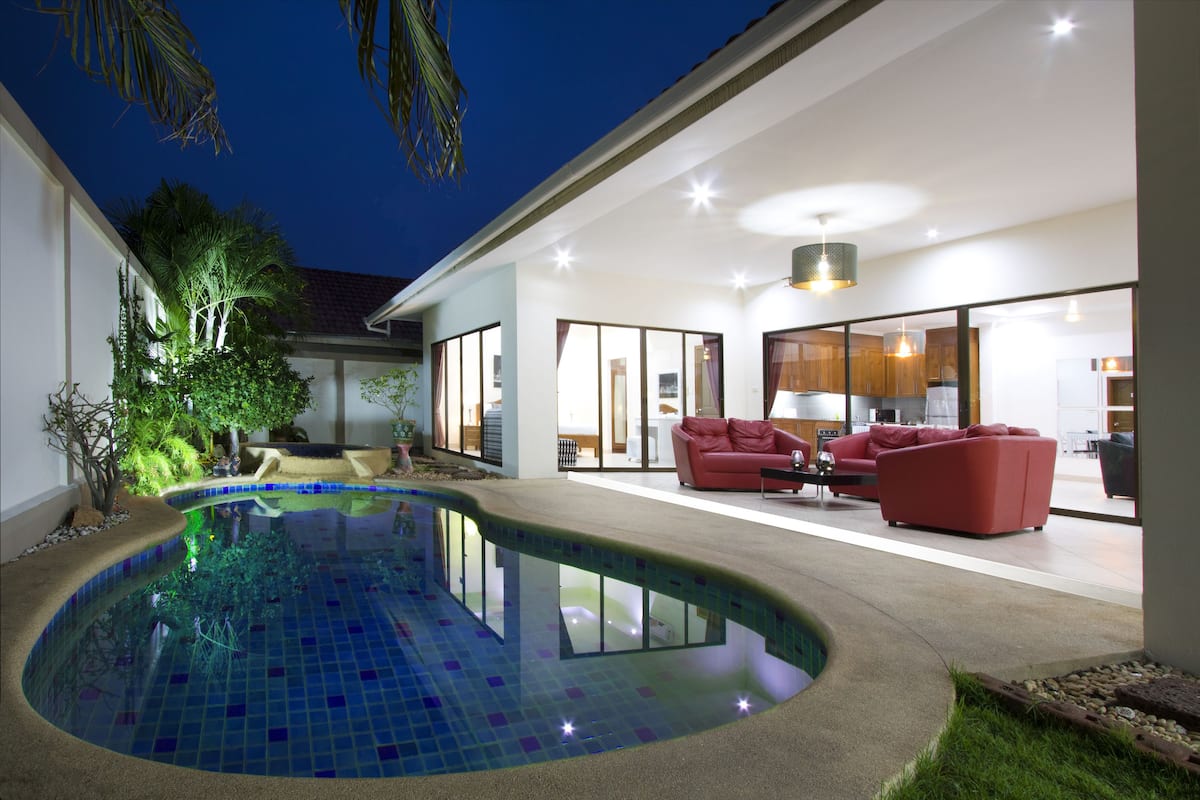 Une maison moderne dotée d’une piscine, de canapés rouges et d’un intérieur bien éclairé.